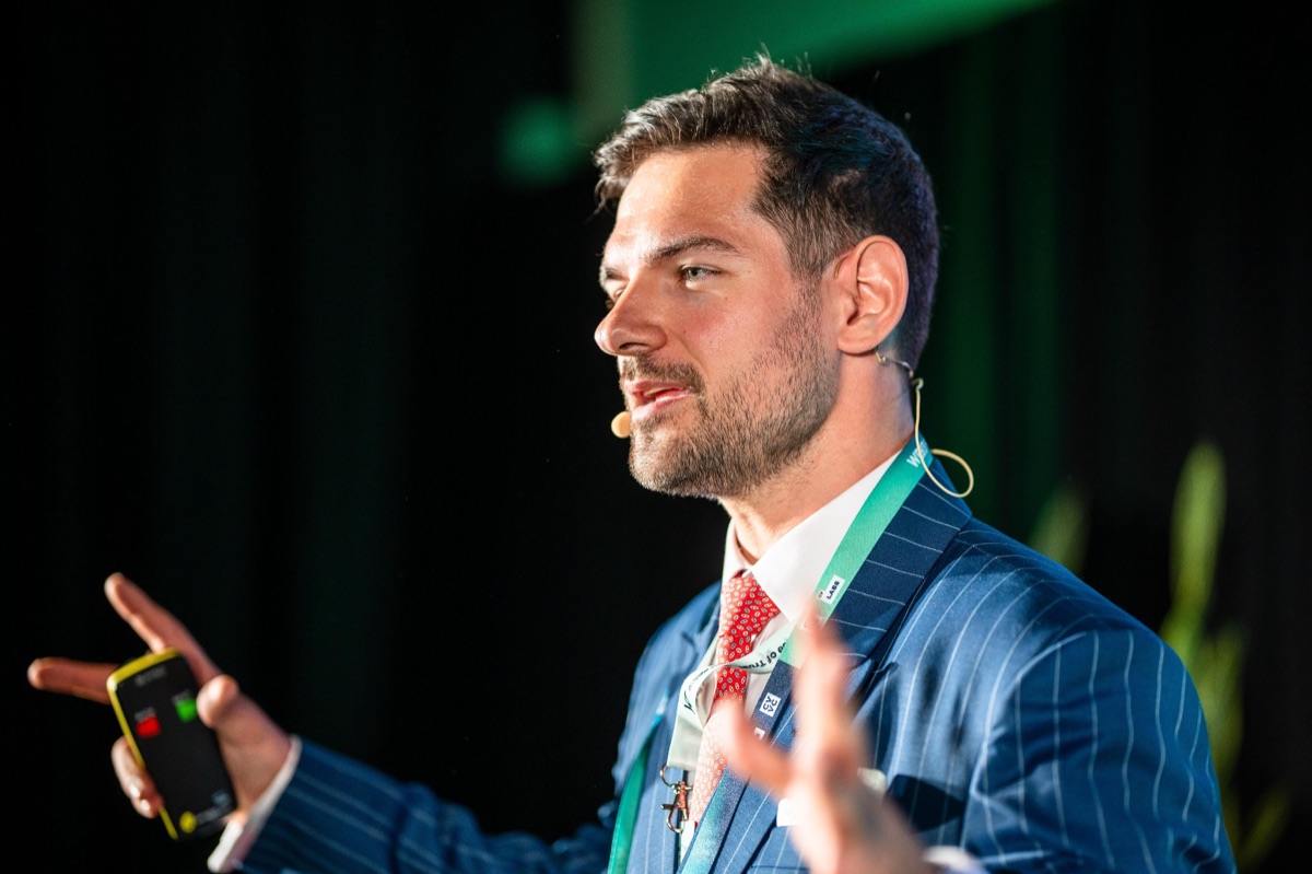 Emanuel Stadler speaking on stage in a blue suit